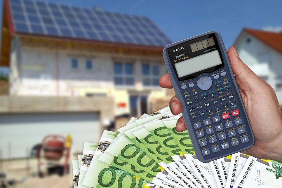 Euro și un calculator, cu o casă pe jumătate construită în fundal.