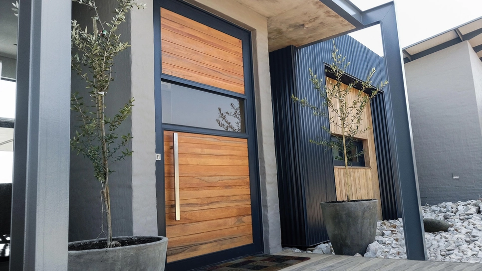 Uși de intrare moderne într-o combinație de lemn, sticlă și aluminiu.