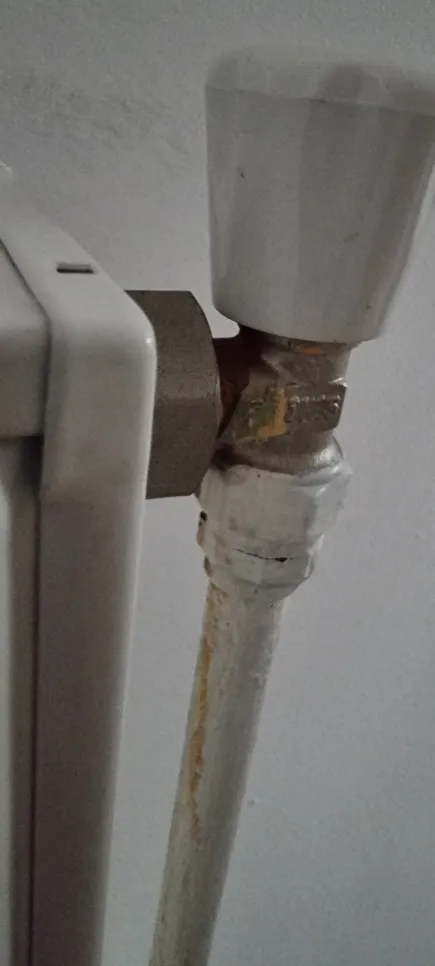 Radiator valve corrosion (38749) Corroded radiator valve with visible rust on pipe and connection joint in a home heating system.