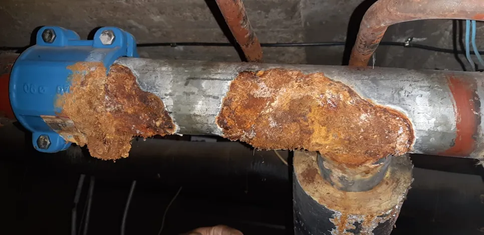 Corroded pipe with significant rust buildup, highlighting potential leakage risk and structural weakness.