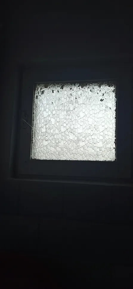Cracked window pane (16924) Heavily cracked window pane with intricate pattern, allowing minimal light through a dimly lit room.